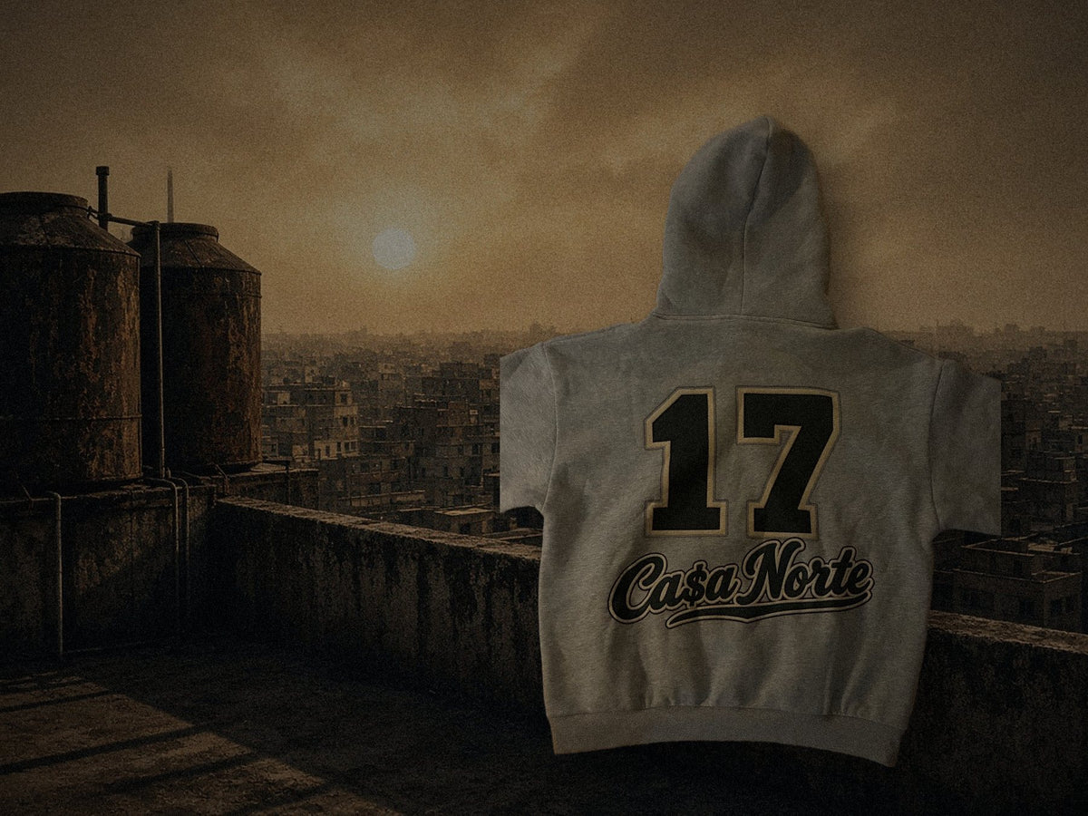 Styled composite: back of the heather gray 17 Ca$a Norte hoodie over a generated rooftop scene, not a product photo